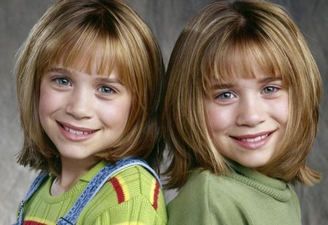 Gêmeas Olsen posam sorrindo quando crianças lado a lado