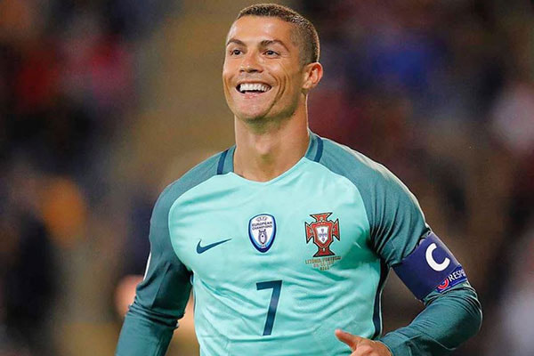 Cristiano Ronaldo sorri enquanto joga bola