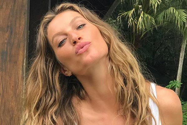 gisele bundchen aparece sorrindo com os cabelos enormes