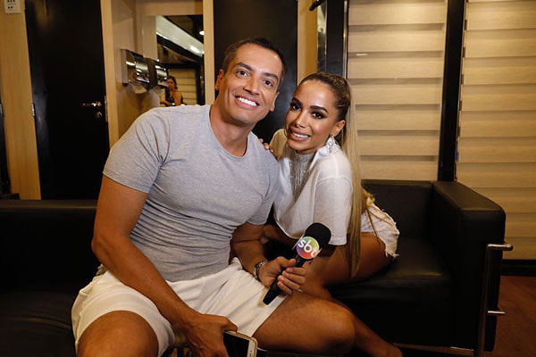 Anitta posa sorrindo junto ao jornalista Leo Dias