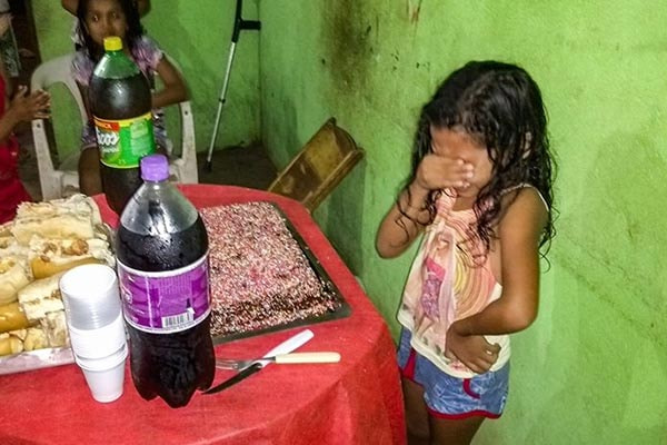 menina chorando na frente de bolo