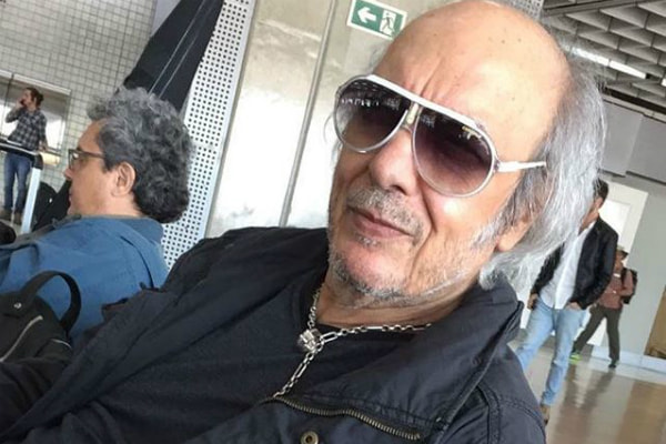 Erasmo Carlos posa de óculos escuros em aeroporto, esperando para fazer escala