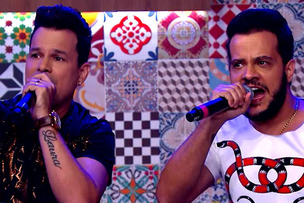 João Neto e Frederico sentados cantando no Programa do Ratinho