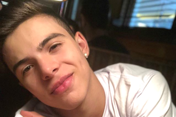 De camiseta branca e relógio preto, Thomaz Costa sorri para selfie