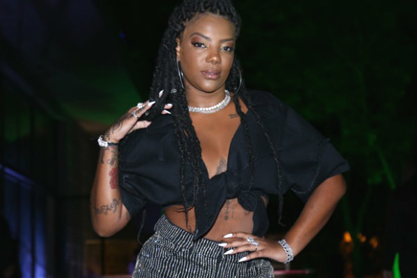 Com uma blusa preta aberta e shorts com pedras em estilo franja, Ludmilla posa sensual