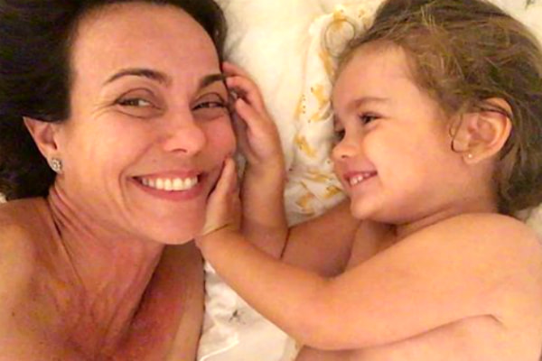 Flávia Monteiro brinca na cama com a filha, Sophia, de dois anos