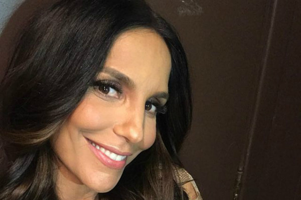 Com cabelo cacheado e maquiagem , Ivete sorri com look dourado