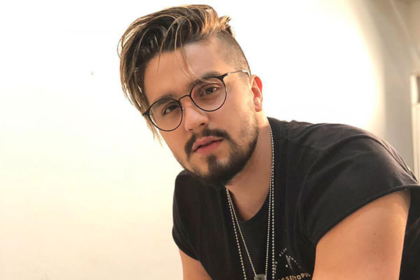 Luan Santana usando camisa preta e cordões de prata