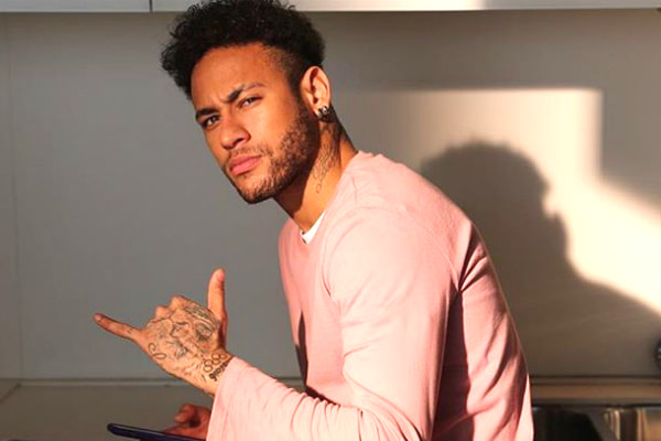 Sentado na pia de casa, Neymar posa para foto fazendo sinal de hang loose