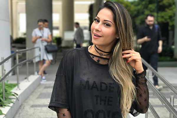 Mayra Cardi com roupa preta pegando nos cabelos na rua