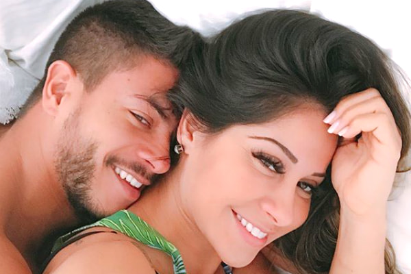 Mayra e o marido Arthur Aguiar sorriem deitados na cama