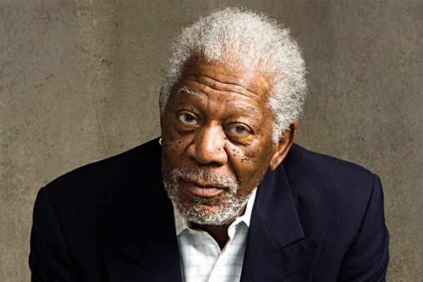 De terno, Morgan Freeman olha atentamente para foto mostrando os cabelos brancos