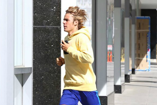 Justin Bieber é flagrado com moleton amarelo e shorts azul correndo na calçada