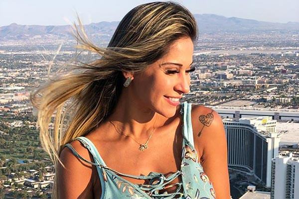 Com vestidinho azul, Mayra posa sorridente à luz do sol