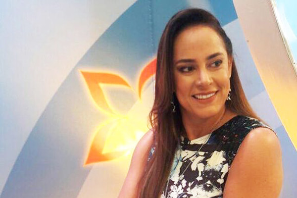 Silvia Abravanel sorri com sentada em uma mesa