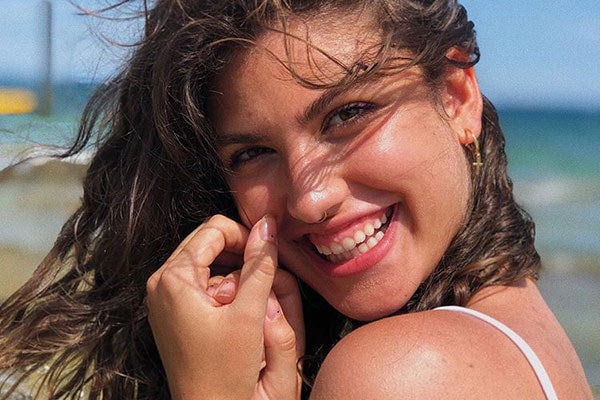 Giovanna Grigio sorrindo para foto na praia