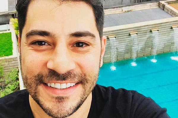 Evaristo Costa posa sorridente em piscina