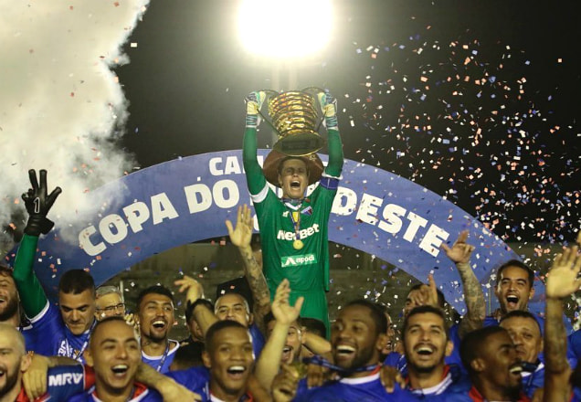Goleiro Marcelo Boeck, capitão do Fortaleza, levanta a taça da Copa do Nordeste, enquanto os demais jogadores da equipe comemoram no gramado