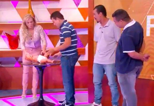 Christina Rocha com pais tentando trocar fralda de boneca