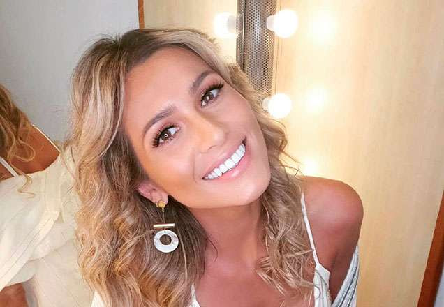 Lívia Andrade sorrindo. Ela está sentada em uma bancada.