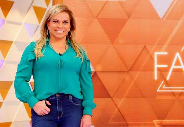 Christina Rocha usa uma blusa verde água e posa com o cenário do Casos de Família atrás dela | Foto: Gabriel Cardoso