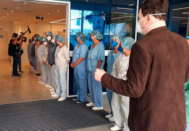 Com máscara, Roberto Cabrini passa no meio de fileira de médicos na porta de hospital de São Paulo