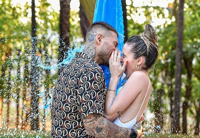 O casal Lucas Lucco e Lorena Carvalho tomando banho de tinta azul