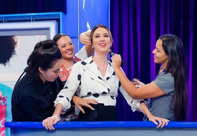 Rebeca está usando uma blusa de bolinhas pretas e aparece sendo preparada para o programa por mais três mulheres | Foto: Gabriel Cardoso/SBT