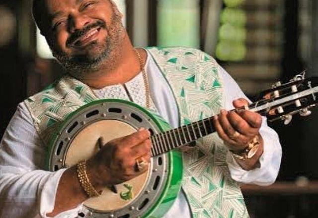 Arlindo Cruz sorrindo e tocando banjo