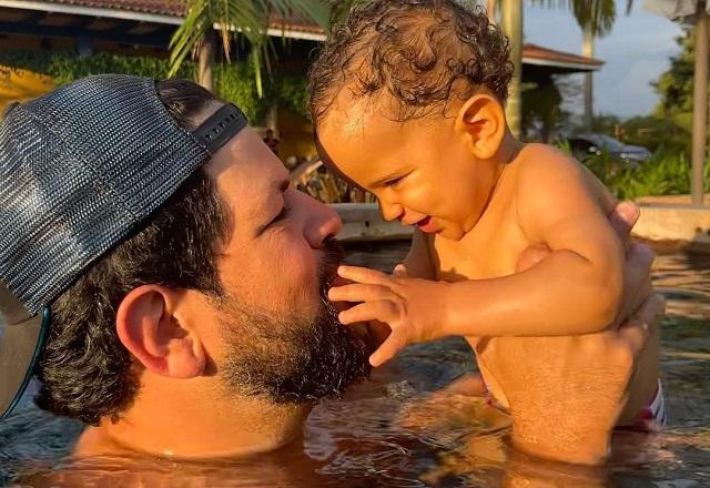 Sorocaba, da dupla com Fernando, segura o filho, Theo, dentro de uma piscina