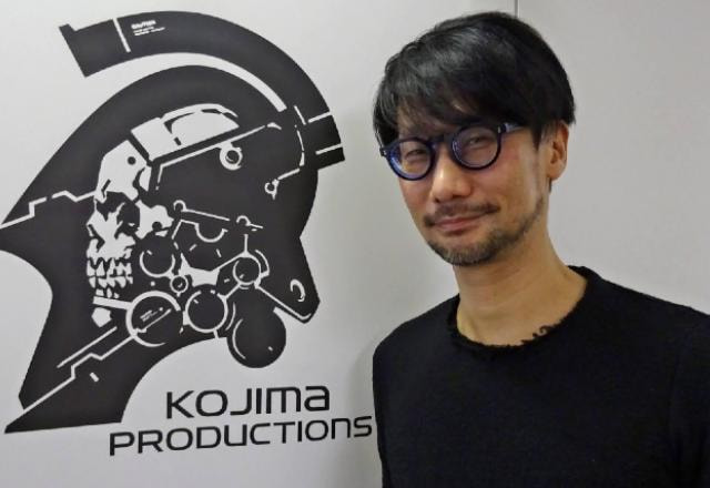 Hideo Kojima na frente do logo da Kojima Productions