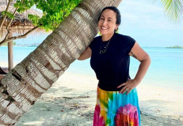 Simone Meina, abraçada em um coqueiro, na praia