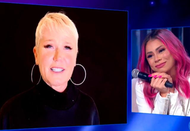Xuxa e Lexa aparecem em duas telas de vídeo. Xuxa à esquerda de blusa preta e Lexa à direita veste blazer branco | Foto: SBT/Reprodução