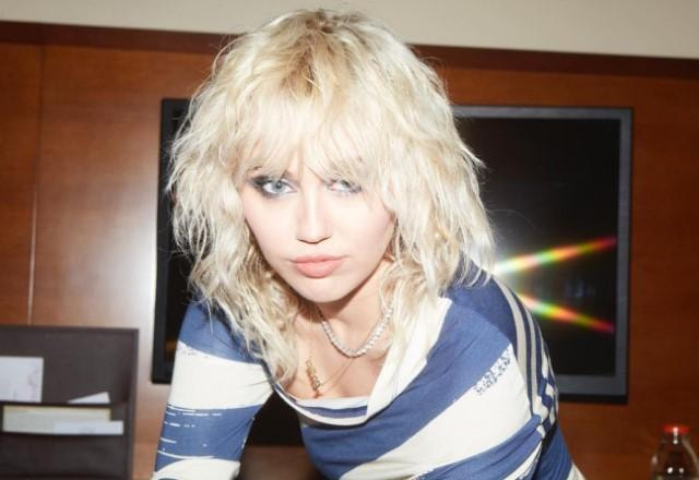 Miley Cyrus posa séria para a câmera usando blusa listrada