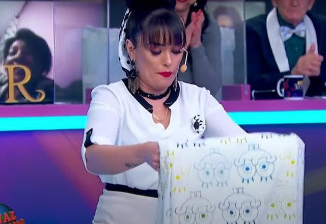 Milene Pavorô dobrando um lençol no palco do Programa do Ratinho