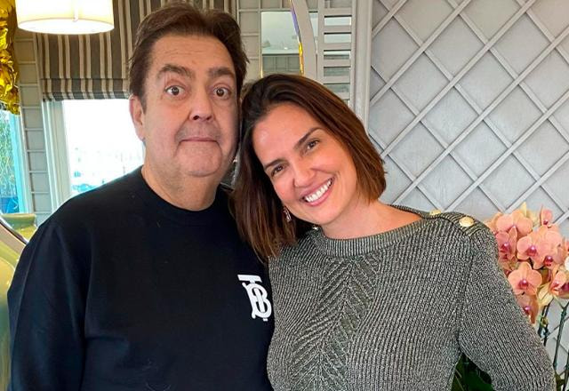 Faustão abraça a esposa Luciana Cardoso na frente de uma parede decorada com Flores | Foto: Reprodução/Instagram