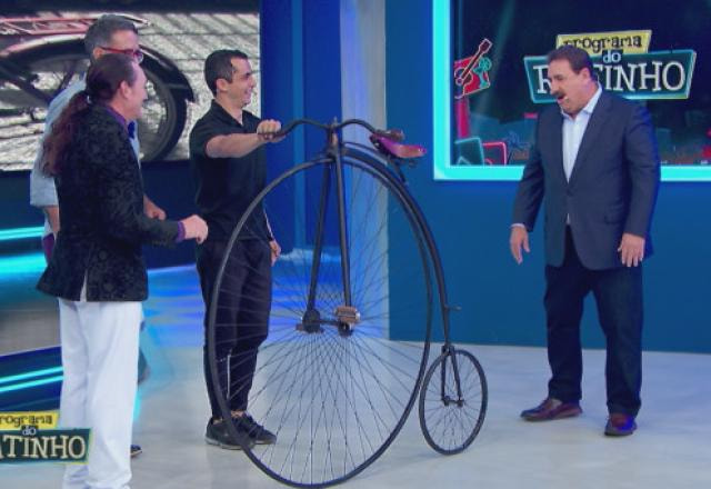 Ratinho e convidados conversando com uma bicicleta no palco.