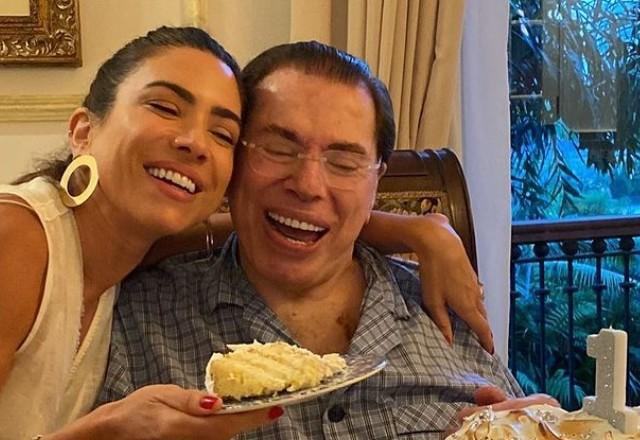 Patricia Abravanel segurando um pedaço de bolo e Silvio Santos comemorando o aniversário do apresentador.