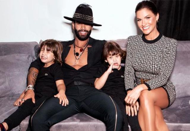 Gusttavo Lima, Andressa Suita e os filhos Samuel e Gabriel sentados em um sofá cinza