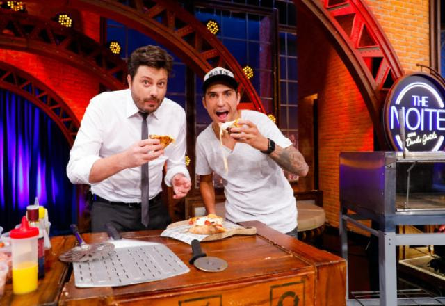 Danilo Gentili e Felipe Prior posam para foto comendo pizza.