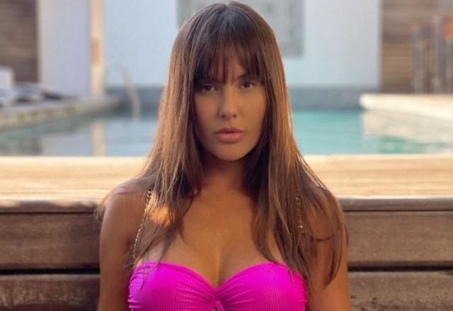 thais braz posa em frente à piscina com cara séria e biquíni rosa