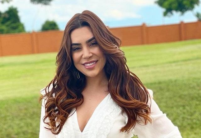 Naiara Azevedo sorri para a câmera; ela está com os cabelos soltos e usa um vestido branco