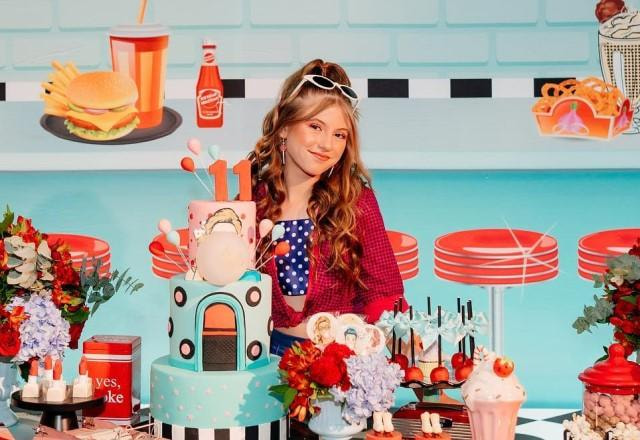 Lorena Queiroz em uma mesa de aniversário com bolo, doces, decoração no estilo pin up