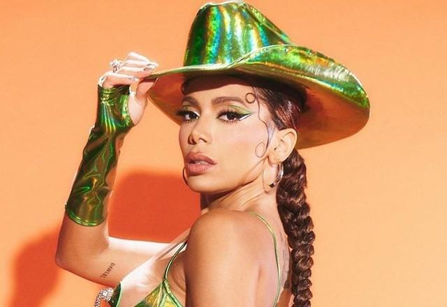 Anitta posa para foto com mão no chapéu.