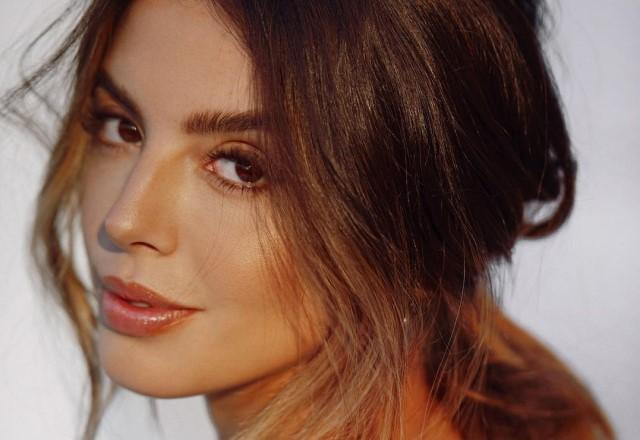 Atriz Giovanna Lancellotti posa de costas olhando para trás e fazendo carão