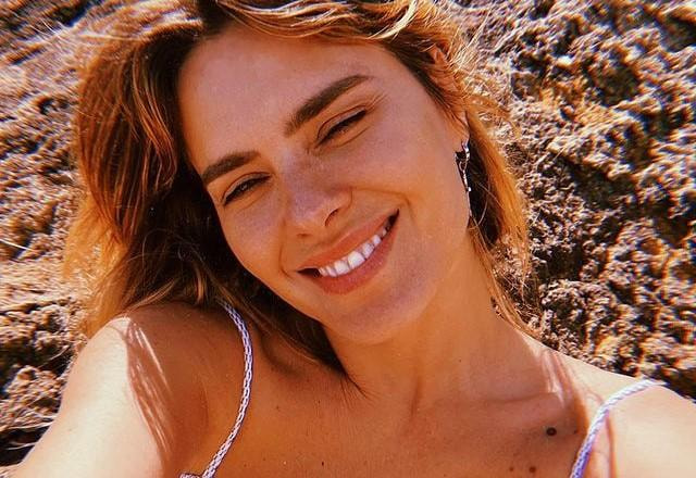 Carolina Dieckman tira selfie sorrindo em praia de Portugal