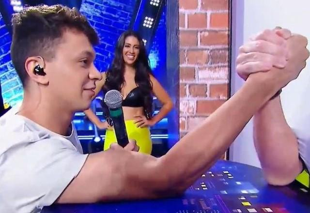 Cocielo fazendo queda de braço no palco do programa.