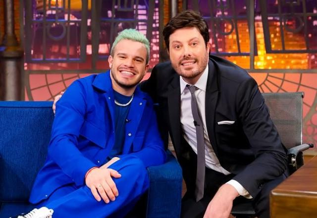 Matheus Fernandes e Danilo Gentili posam para foto no palco do programa.