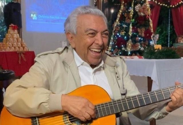 Mauricio de Sousa segurando um violão como se estivesse tocando e rindo bastante