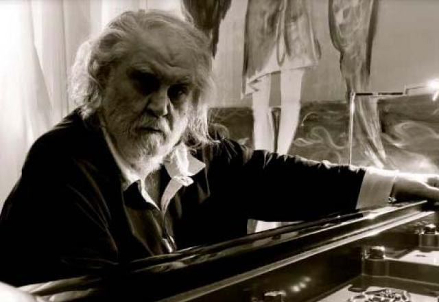 O compositor grego Vangelis sentado em frente ao piano